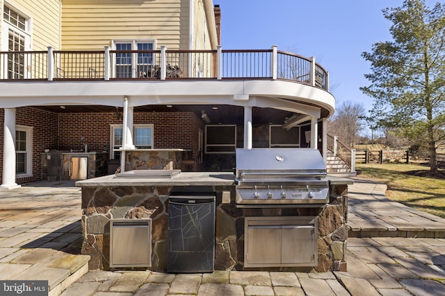 view of patio / terrace with grilling area, a balcony, and an outdoor kitchen