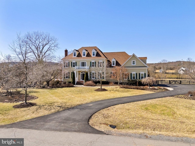 view of front of house featuring a chimney, a front yard, and fence