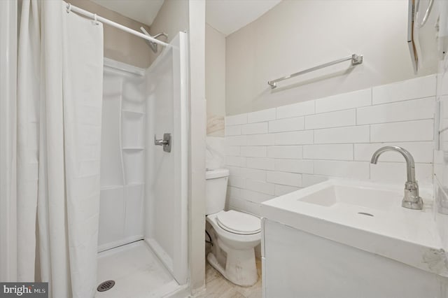 bathroom featuring wainscoting, toilet, vanity, a shower stall, and tile walls