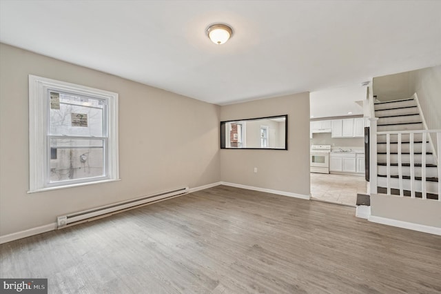 unfurnished living room with light wood-type flooring, a baseboard radiator, baseboards, and stairs