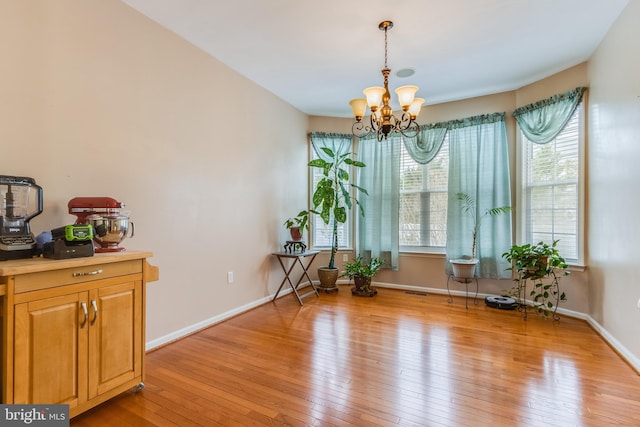 living area with light wood-style floors, a notable chandelier, and baseboards