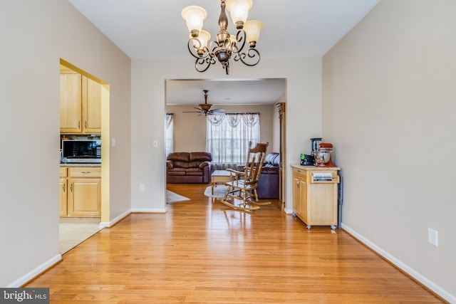 interior space featuring light wood-style floors, baseboards, and ceiling fan with notable chandelier