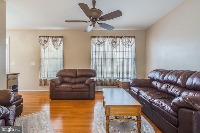 living room with a fireplace, ceiling fan, baseboards, and wood finished floors