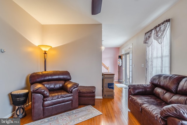 living area with light wood-type flooring, baseboards, and a ceiling fan