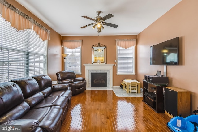 living room with ceiling fan, a fireplace with flush hearth, wood-type flooring, and a wealth of natural light