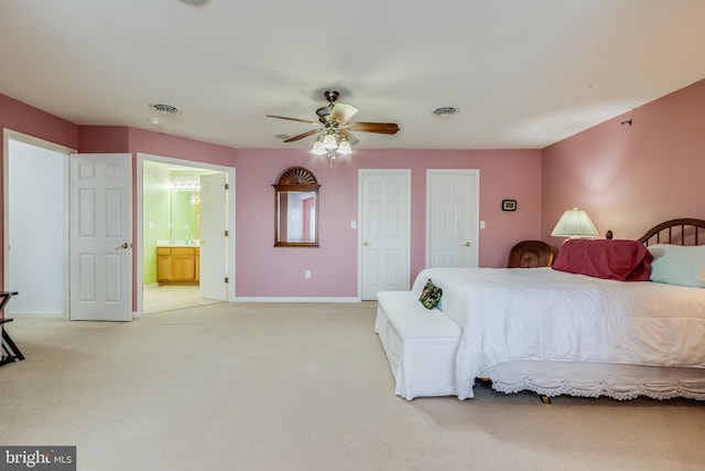 bedroom with light carpet, visible vents, baseboards, a ceiling fan, and ensuite bathroom