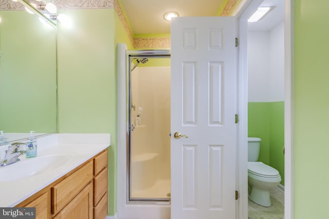 bathroom with a stall shower, vanity, and toilet