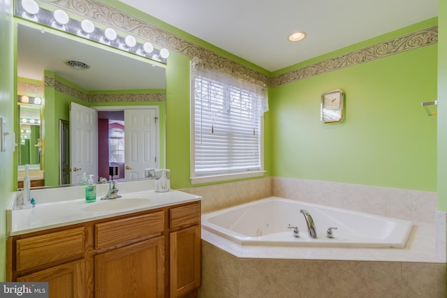 bathroom featuring a whirlpool tub, a healthy amount of sunlight, visible vents, and vanity