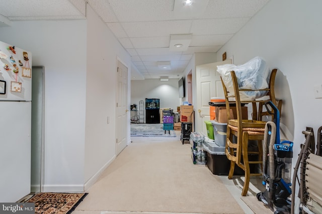 hall with baseboards, a drop ceiling, and carpet flooring