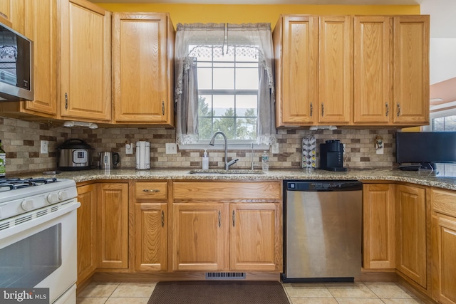 kitchen with light tile patterned floors, visible vents, appliances with stainless steel finishes, a sink, and light stone countertops