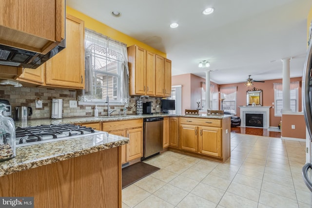 kitchen with dishwasher, open floor plan, a peninsula, ornate columns, and a fireplace