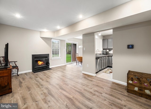 living room featuring a fireplace with flush hearth, baseboards, recessed lighting, and light wood-type flooring