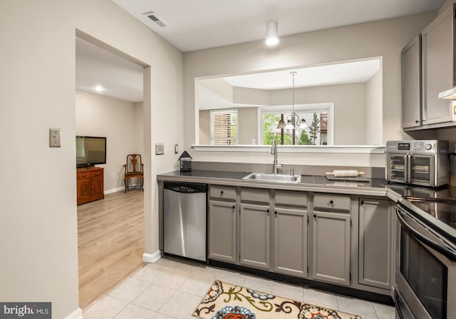 kitchen with gray cabinets, stainless steel appliances, and a sink