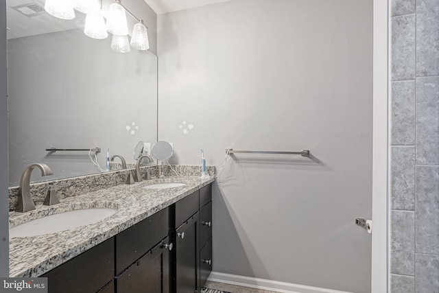 full bath featuring a sink, visible vents, baseboards, and double vanity