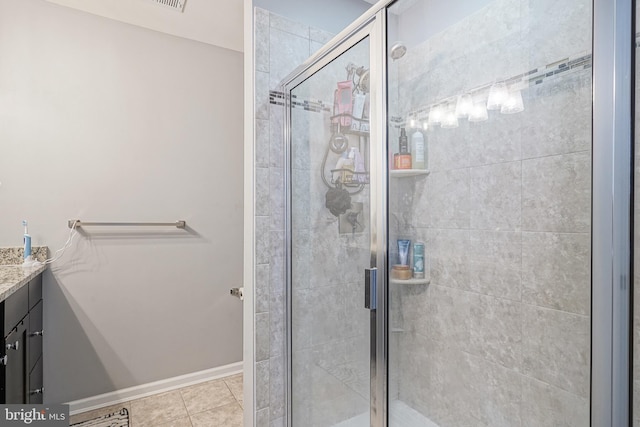 full bathroom featuring vanity, baseboards, a stall shower, and tile patterned flooring