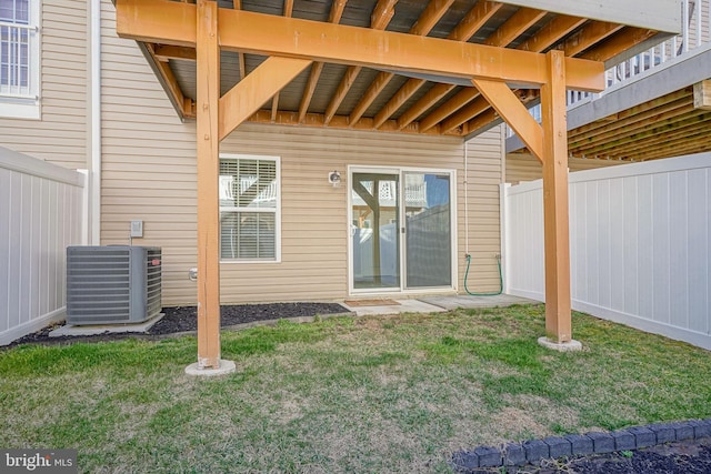 property entrance featuring central air condition unit, a lawn, and fence