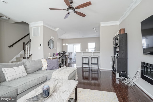 living area with visible vents, ornamental molding, dark wood-style floors, baseboards, and stairs