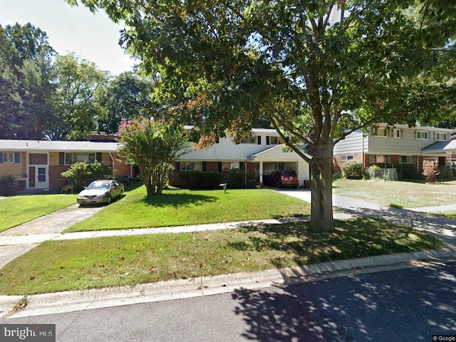 view of front of home with concrete driveway, brick siding, and a front lawn