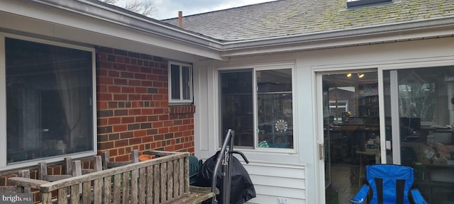 exterior space with a shingled roof and brick siding