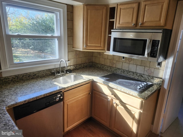 kitchen with tasteful backsplash, dark wood finished floors, appliances with stainless steel finishes, stone counters, and a sink