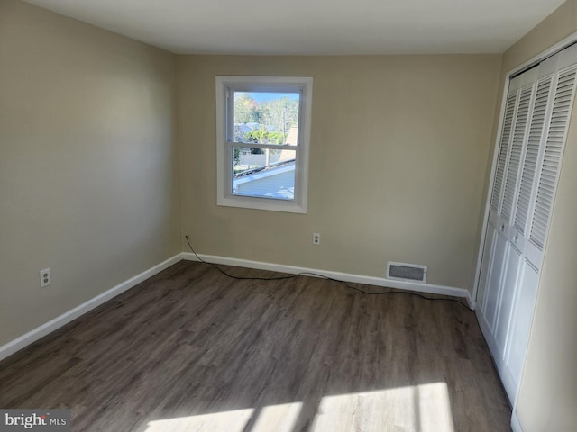 unfurnished bedroom with wood finished floors, visible vents, and baseboards