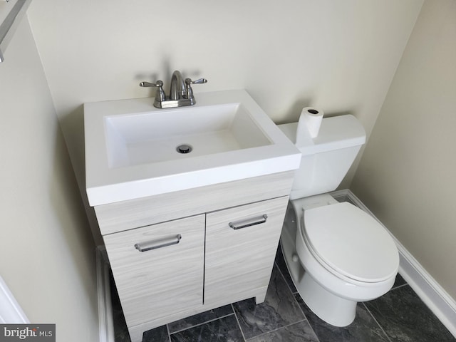 bathroom featuring marble finish floor, baseboards, vanity, and toilet