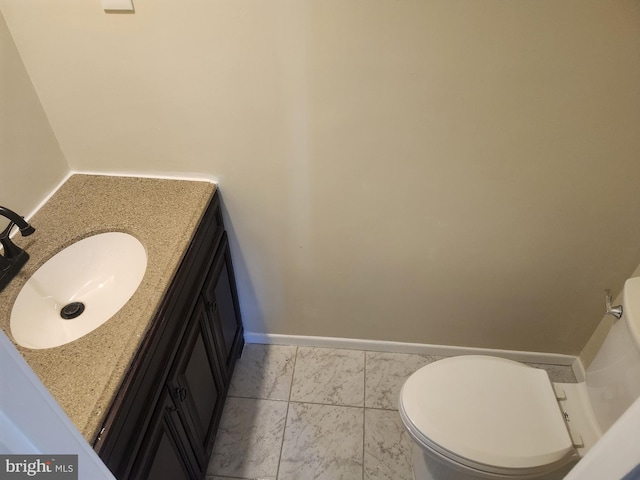 bathroom featuring marble finish floor, baseboards, vanity, and toilet