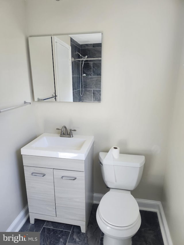 bathroom with toilet, marble finish floor, baseboards, and vanity