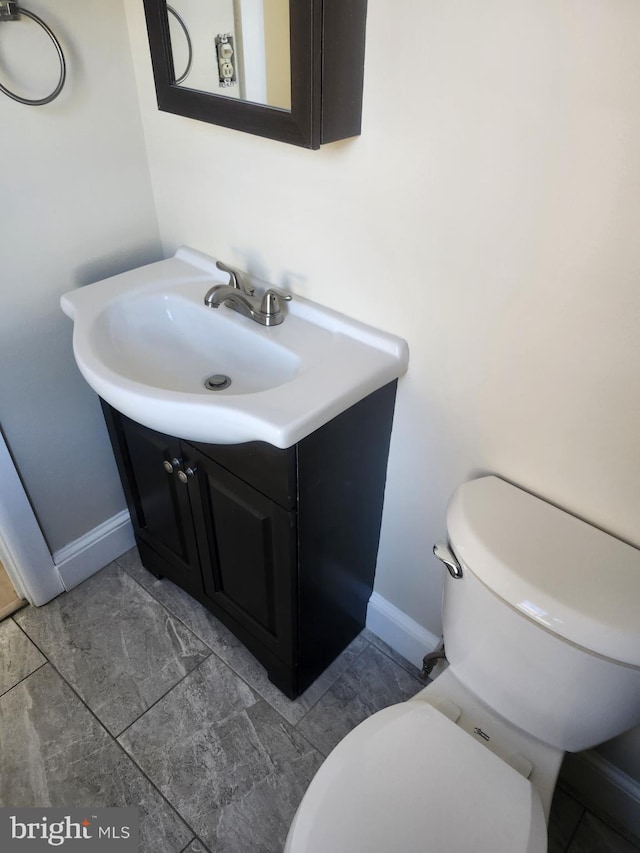 bathroom with vanity, toilet, and baseboards