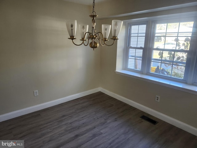 unfurnished dining area featuring dark wood-style floors, baseboards, visible vents, and a chandelier