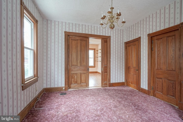 unfurnished bedroom with wallpapered walls, baseboards, and a textured ceiling