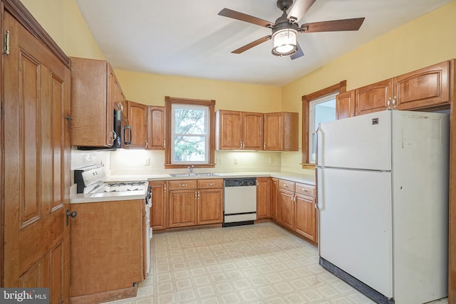 kitchen with light floors, light countertops, brown cabinets, white appliances, and a sink