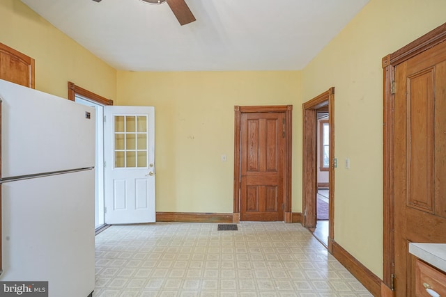 kitchen featuring light floors, baseboards, freestanding refrigerator, light countertops, and brown cabinets