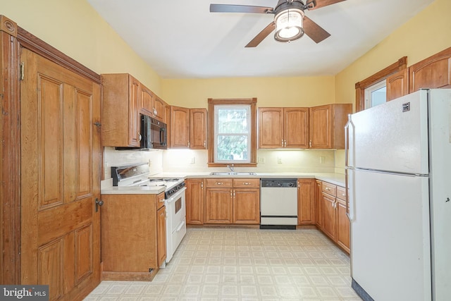 kitchen featuring light floors, white appliances, light countertops, and a sink