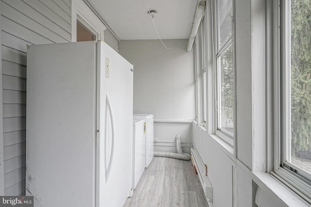 corridor featuring washer and dryer, light wood-style flooring, and a healthy amount of sunlight