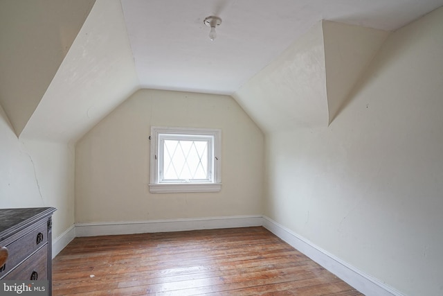 bonus room featuring baseboards, vaulted ceiling, and light wood finished floors