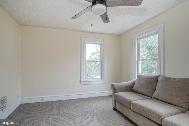 sitting room with baseboards, carpet floors, a textured ceiling, and ceiling fan