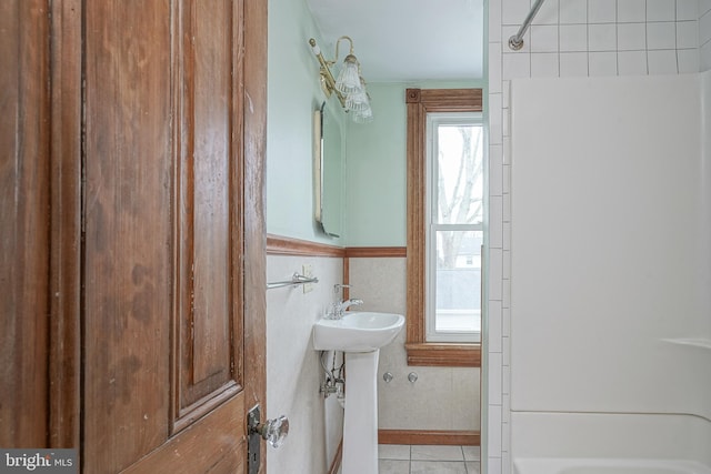 bathroom featuring tile walls, tub / shower combination, tile patterned floors, and wainscoting