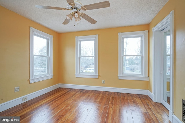 spare room with a ceiling fan, baseboards, wood-type flooring, and a textured ceiling