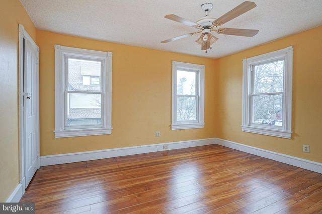 empty room with hardwood / wood-style floors, baseboards, and a textured ceiling