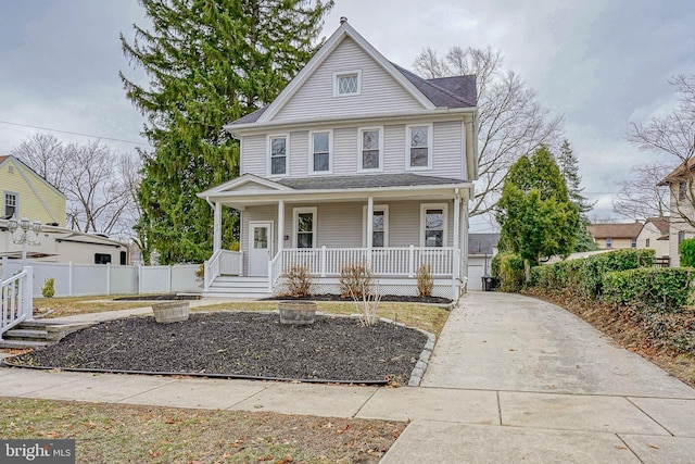 view of front of home with covered porch, driveway, and fence