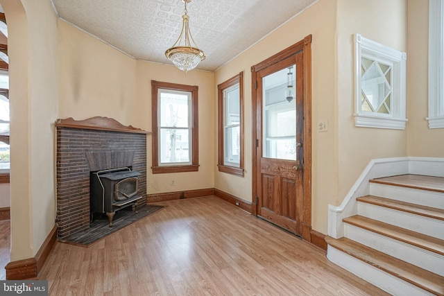 foyer entrance featuring an ornate ceiling, wood finished floors, arched walkways, baseboards, and a wood stove