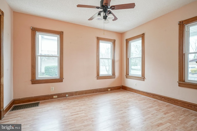 unfurnished room featuring visible vents, plenty of natural light, and wood finished floors