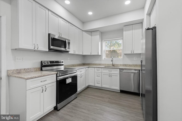 kitchen with white cabinetry, stainless steel appliances, and a sink