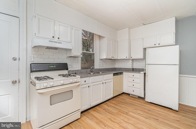 kitchen with white appliances, under cabinet range hood, light wood-style floors, and a sink