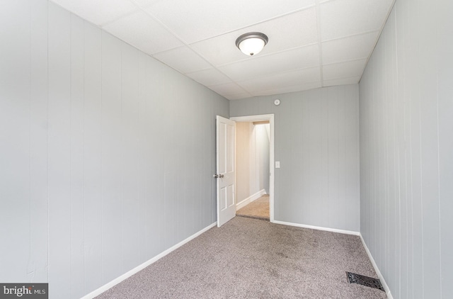 empty room featuring a paneled ceiling, baseboards, visible vents, and carpet flooring