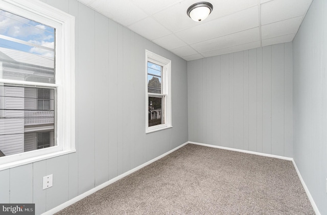 carpeted empty room with baseboards and a drop ceiling