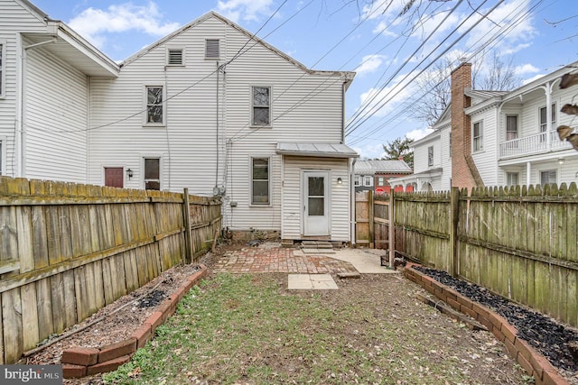 rear view of house with entry steps, a patio area, and a fenced backyard