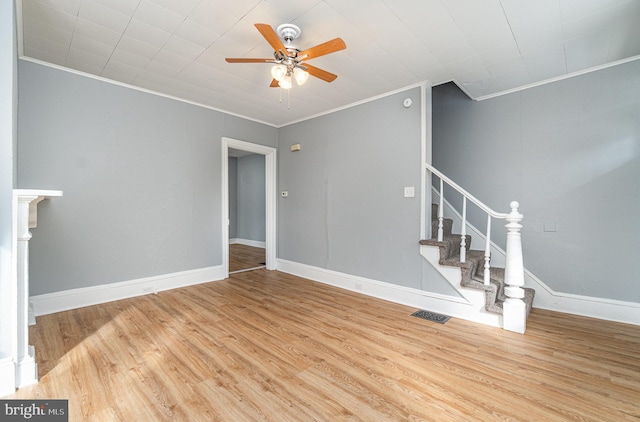 spare room with stairway, crown molding, visible vents, and wood finished floors