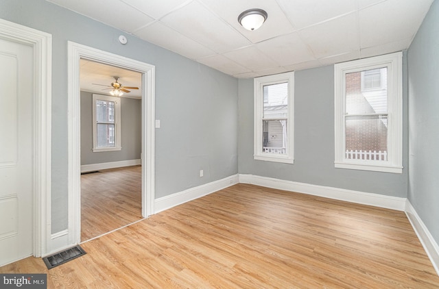 empty room featuring visible vents, a paneled ceiling, light wood-style flooring, and baseboards